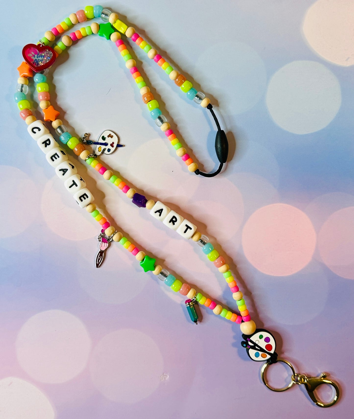 The paint palette, brush, pencil, heart, and other art-themed charms that are on the lanyard.