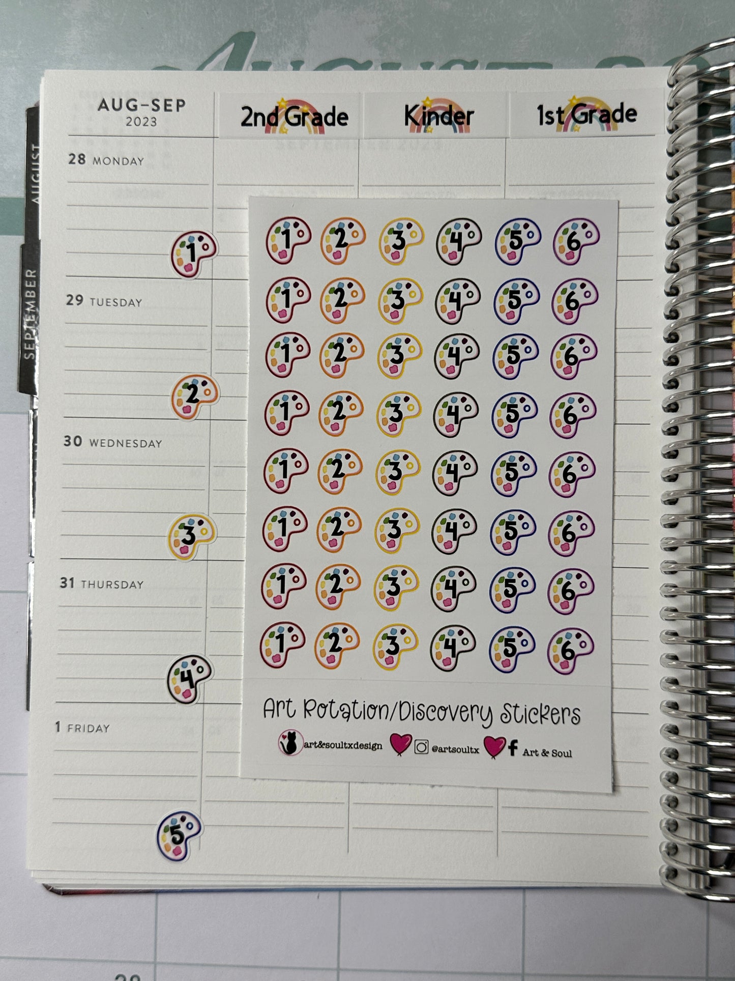 A Six Day Art Class Rotation Schedule sticker sheet placed on an open Eric Condren teacher planner. Rotation Day stickers have been placed on the corners of each calendar day to help the teacher identify and track which rotation day on their schedule.