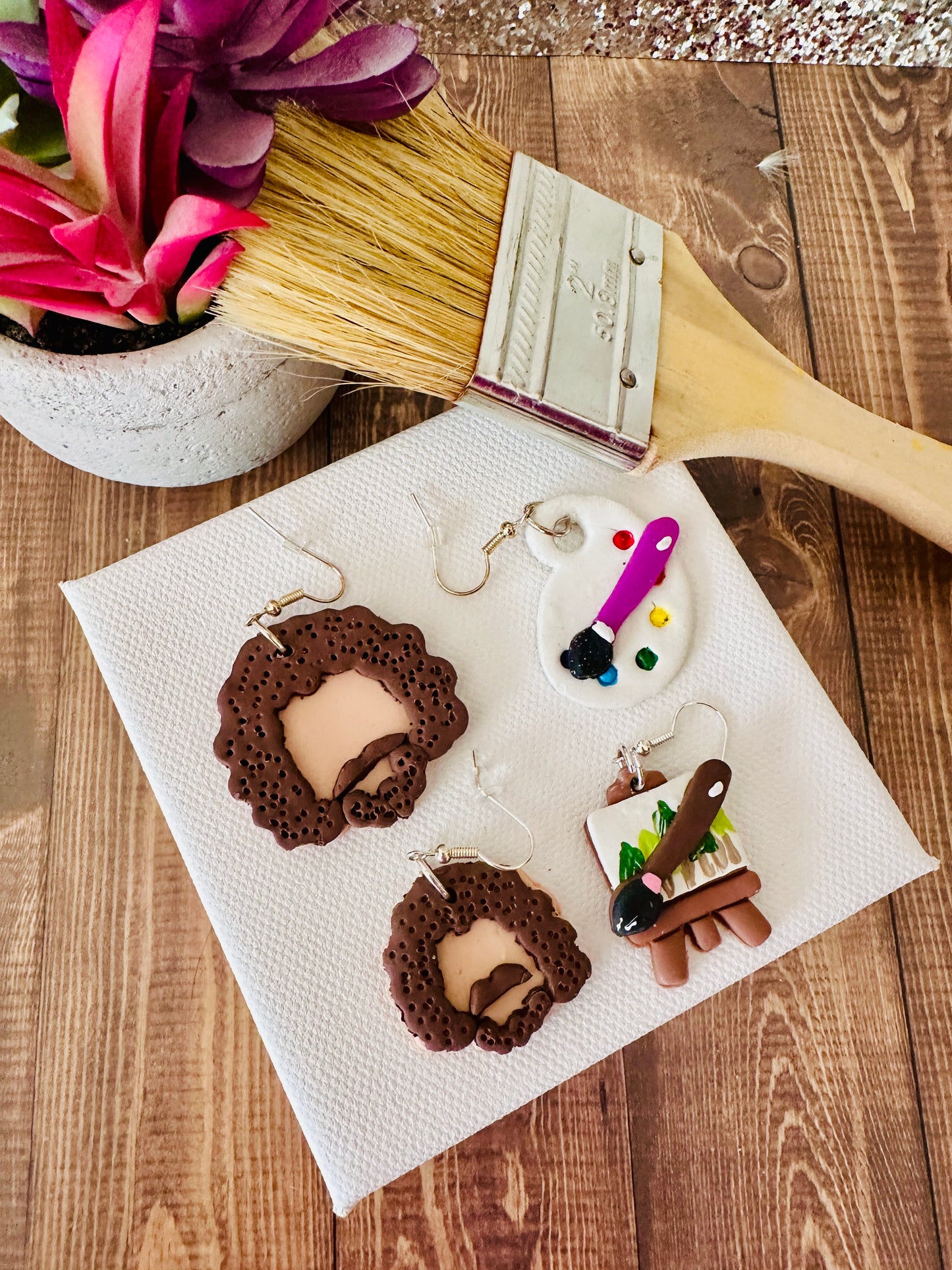 An angled view of Bob Ross polymer clay earrings showing the large and small variants so shoppers can compare sizes.