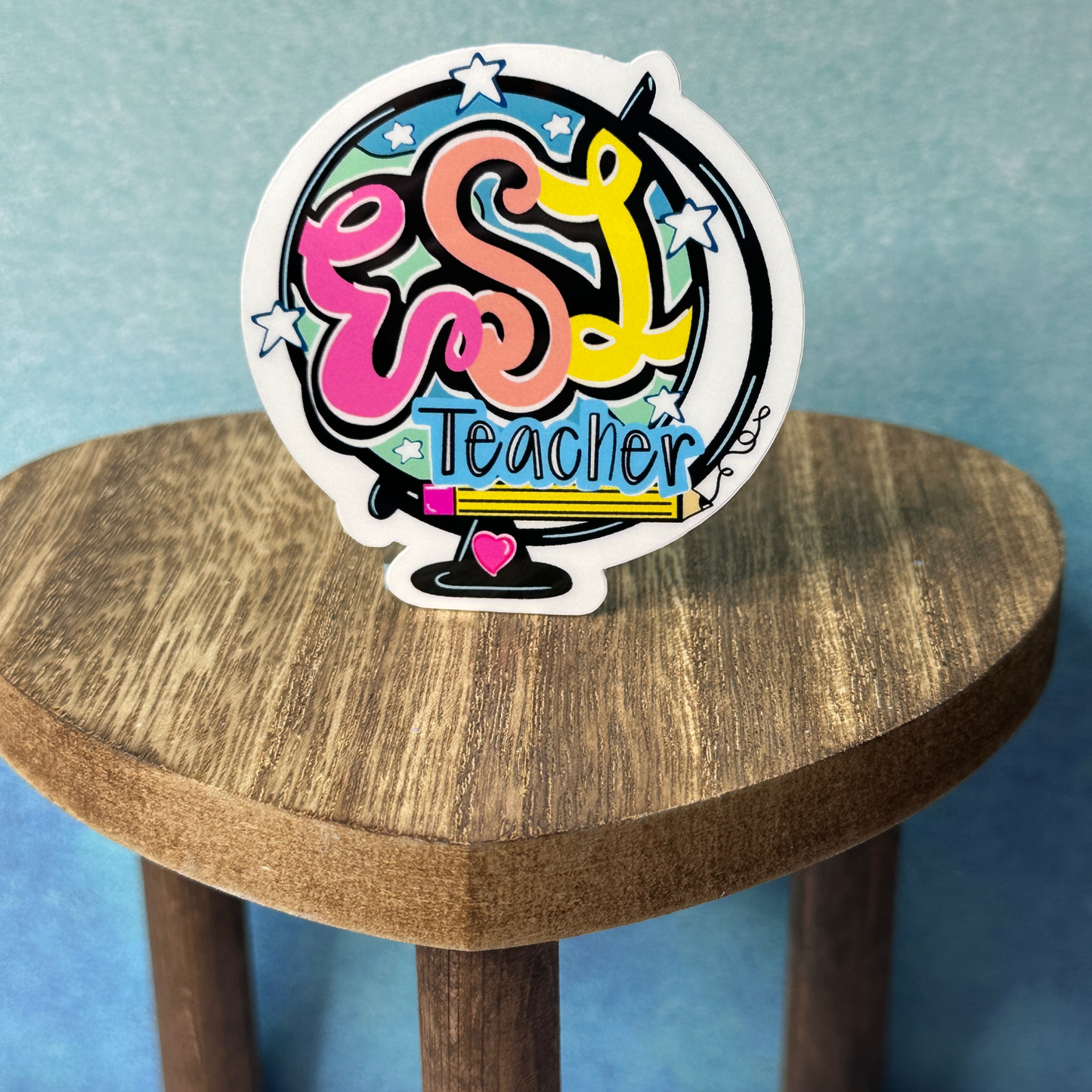 Hand-drawn ESL teacher waterproof vinyl sticker displayed on heart-shaped wooden table with blue wall background decor