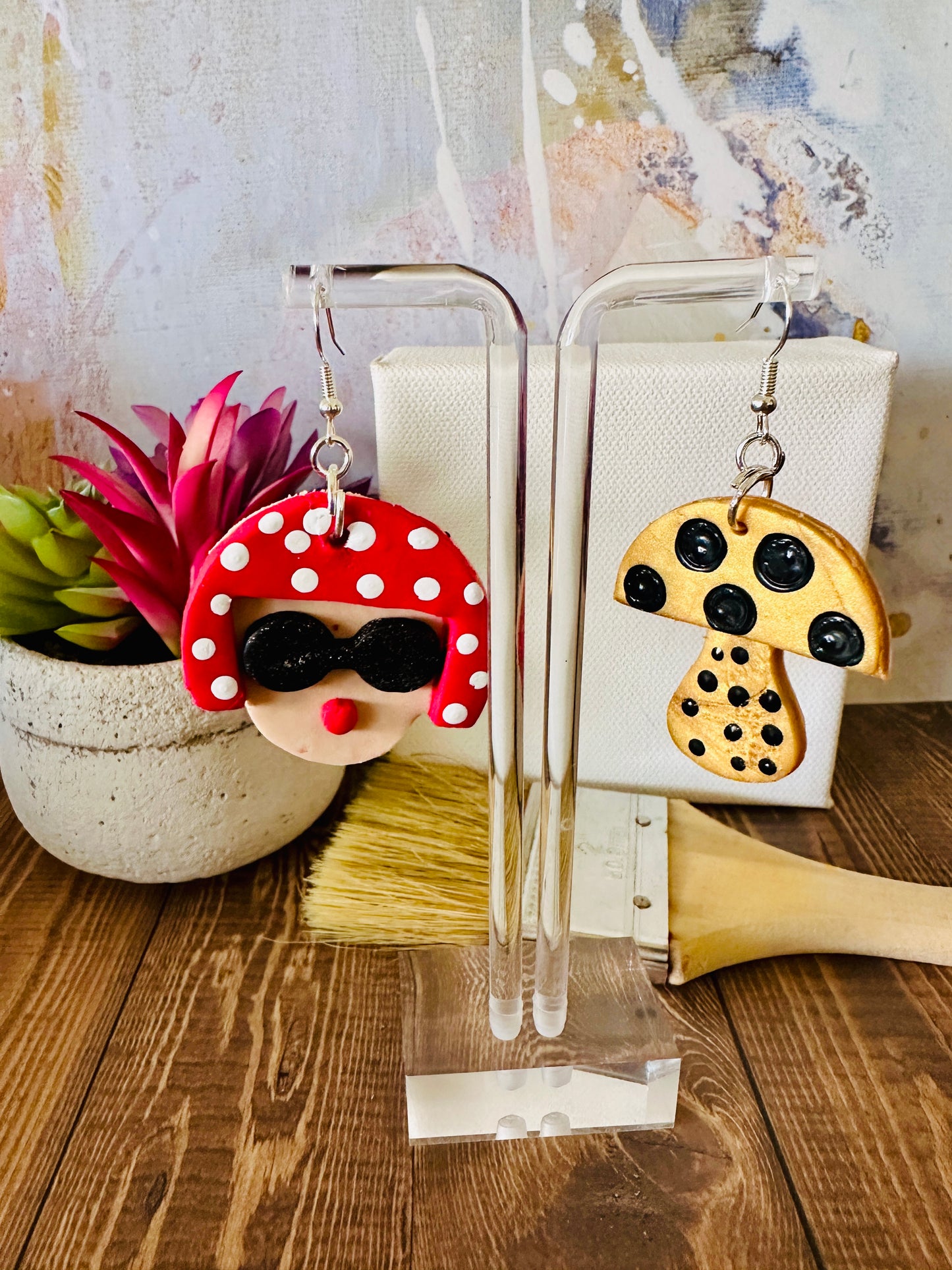 "Close-up detail of large Yayoi Kusama polymer clay earrings showing artistic portrait with red polka dot hair, black sunglasses, red lips.