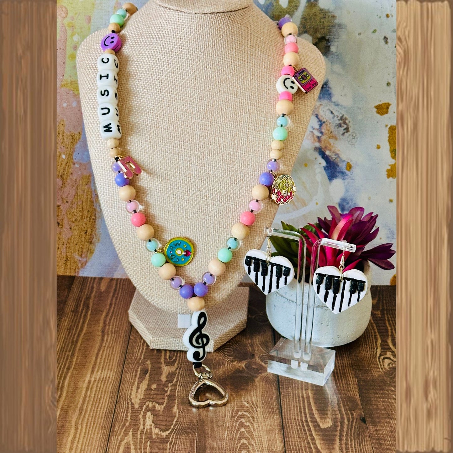 Colorful beaded necklace with musical-themed charms on a wooden base.