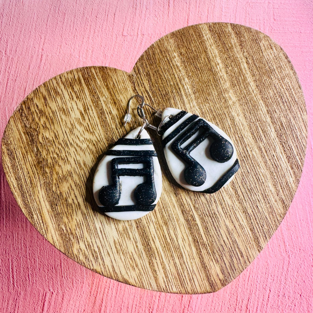 A set of musical note earrings on a wooden table shaped like a heart.