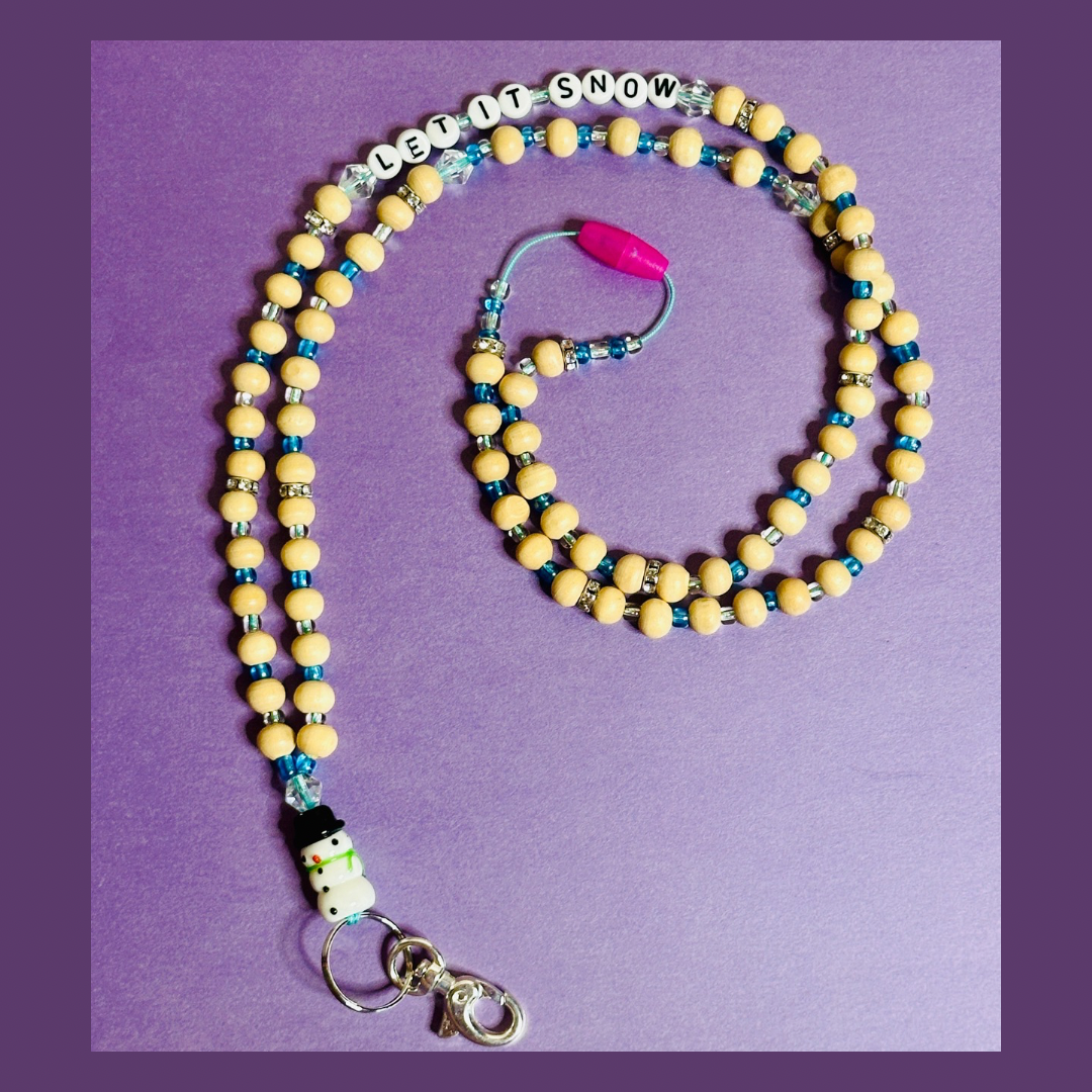 The full Snowman Christmas Lanyard on a purple background. The lanyard is in a spiral shape and the beaded words "LET IT SNOW" are seen on the top string of the lanyard.