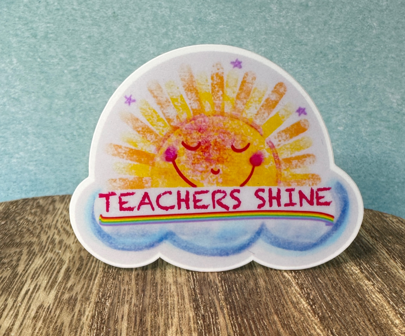 Teachers Shine waterproof vinyl sticker displayed on a wooden table in front of a blue wall.
