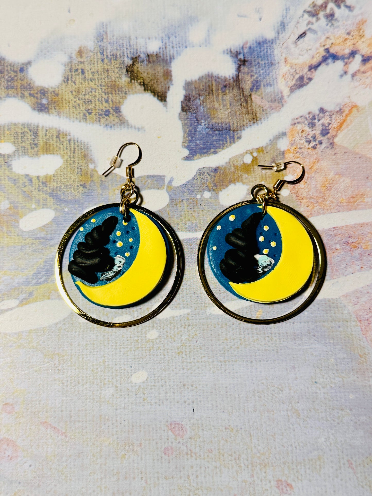 A pair of Van Gogh Starry Night earrings on an abstract colored background.