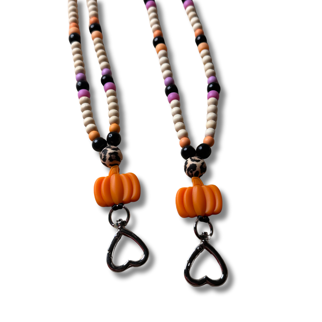 Close-up view of two fall pumpkin lanyards showing detailed wooden beads, breakaway clasp, and heart-shaped metal keyholder - ideal for teachers and fall enthusiasts.