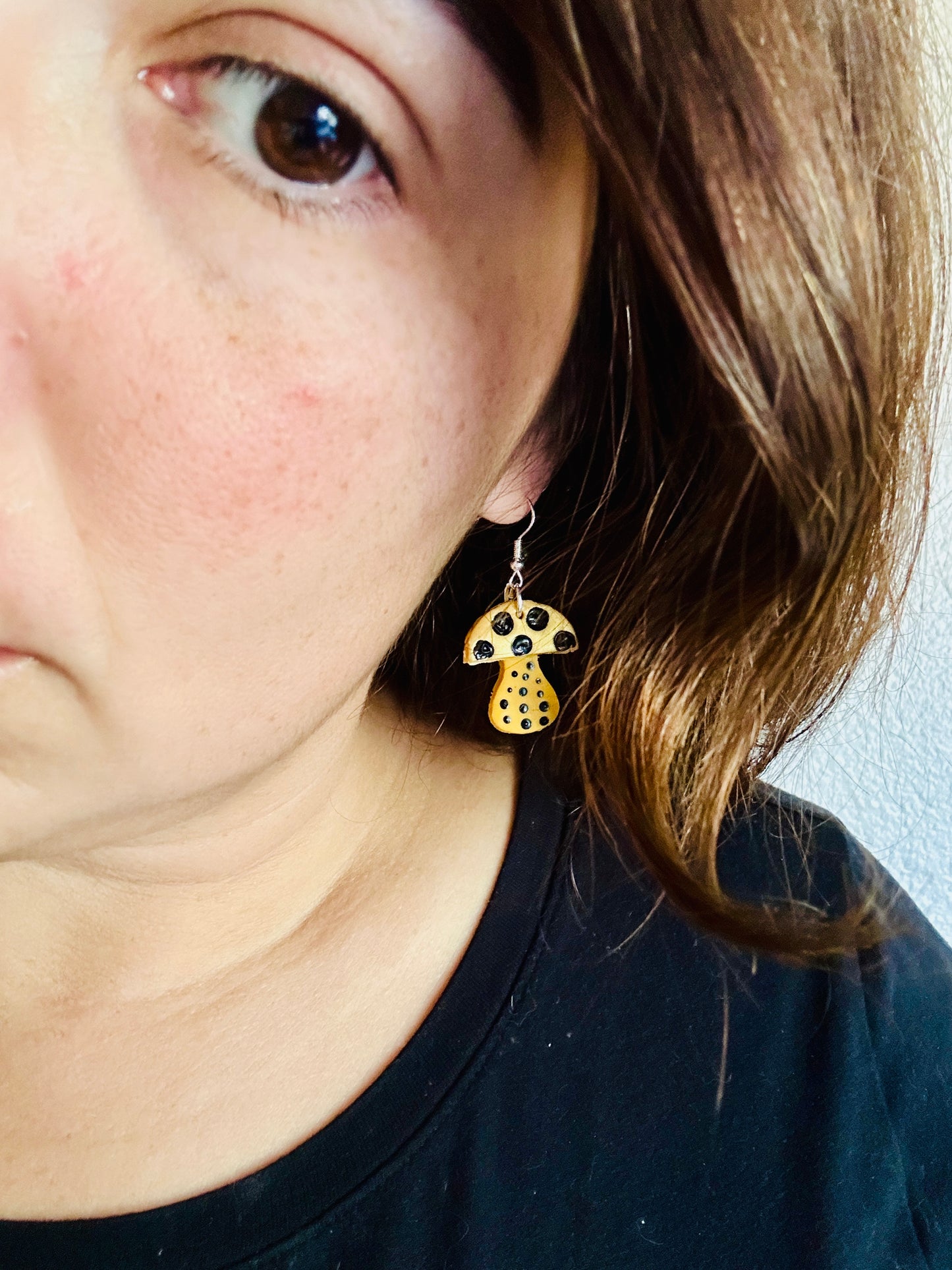 Woman wearing Yayoi Kusama inspired polymer clay earrings showing yellow mushroom with black polka dots, perfect statement jewelry for artists.