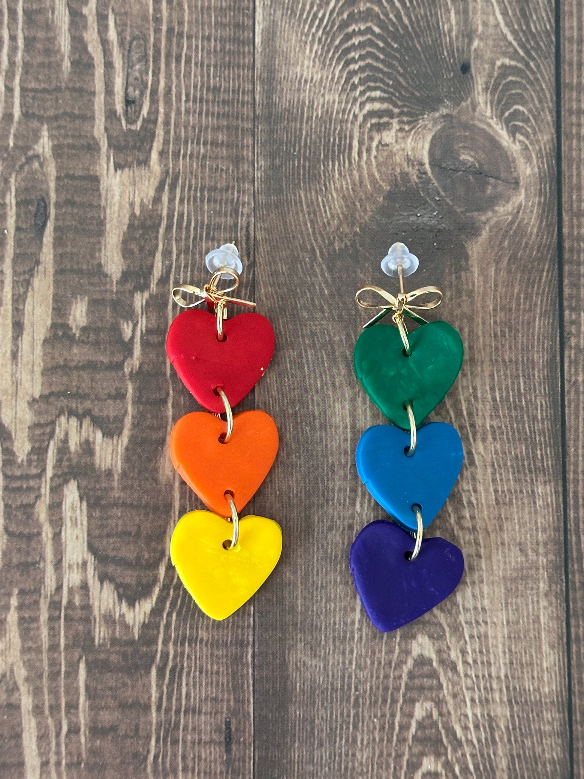 Colorful heart-shaped earrings on a wooden surface