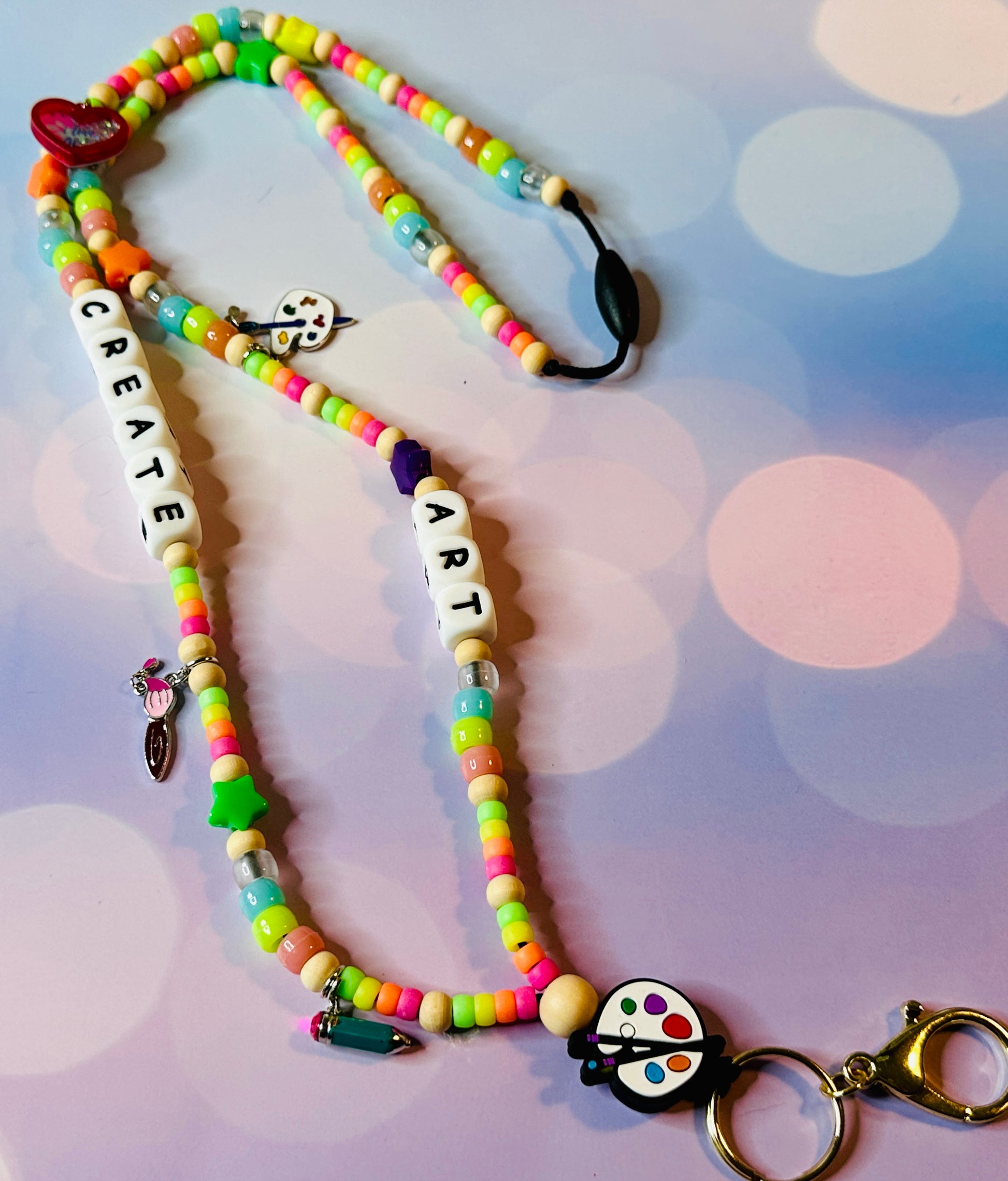 Colorful letter beads spelling CREATE ART on the handmade art teacher lanyard