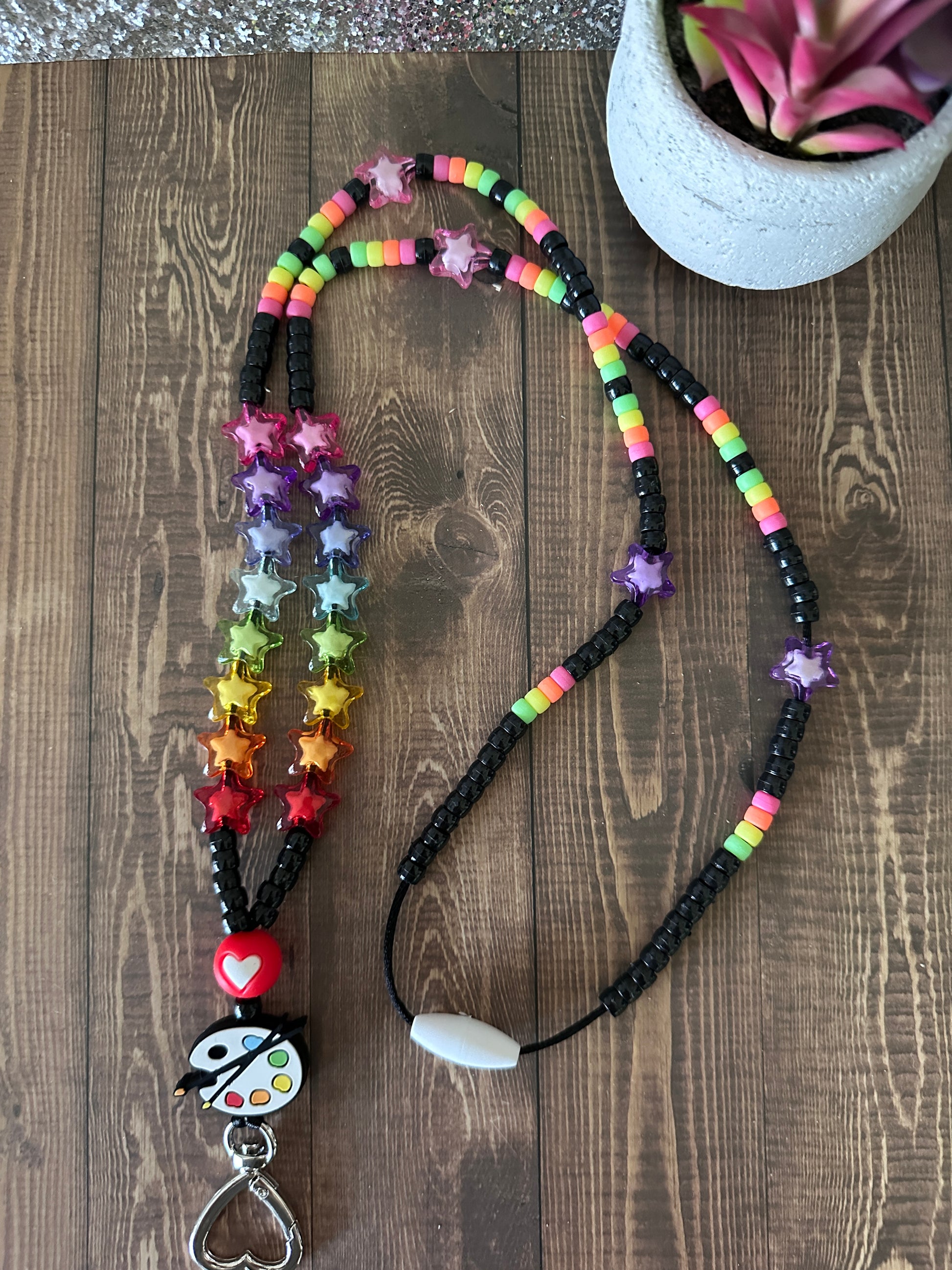 Overhead view of art teacher lanyard in different position on dark wooden table.
