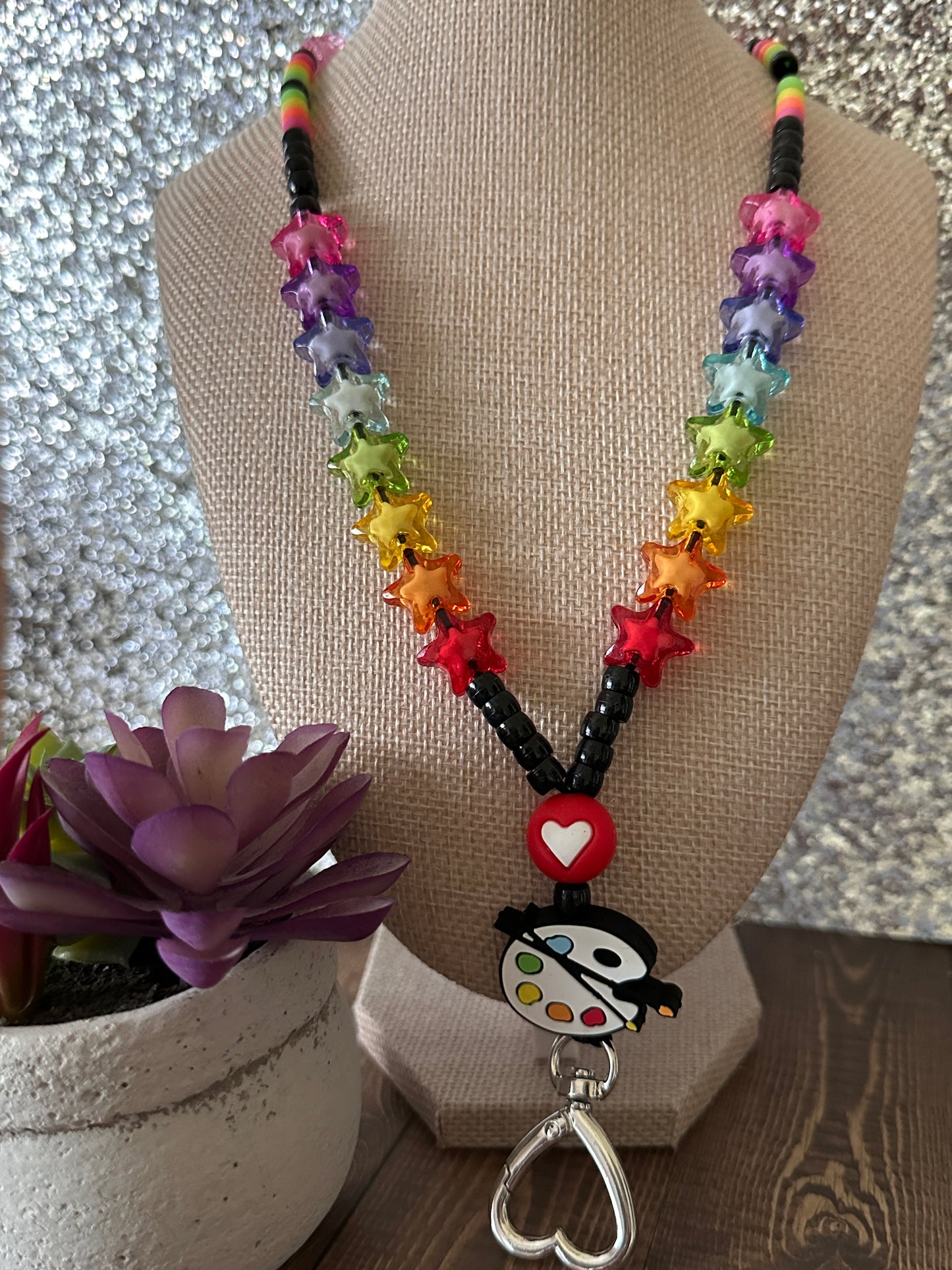 Art teacher lanyard on tan mannequin showcasing paint palette bead with succulent and glitter background.