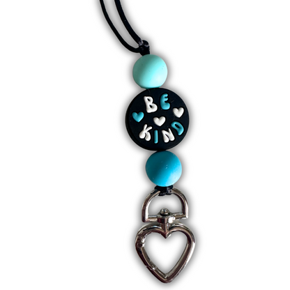 Close-up view of blue Be Kind lanyard showing heart-shaped clasp for keys and safety breakaway mechanism designed for classroom safety.