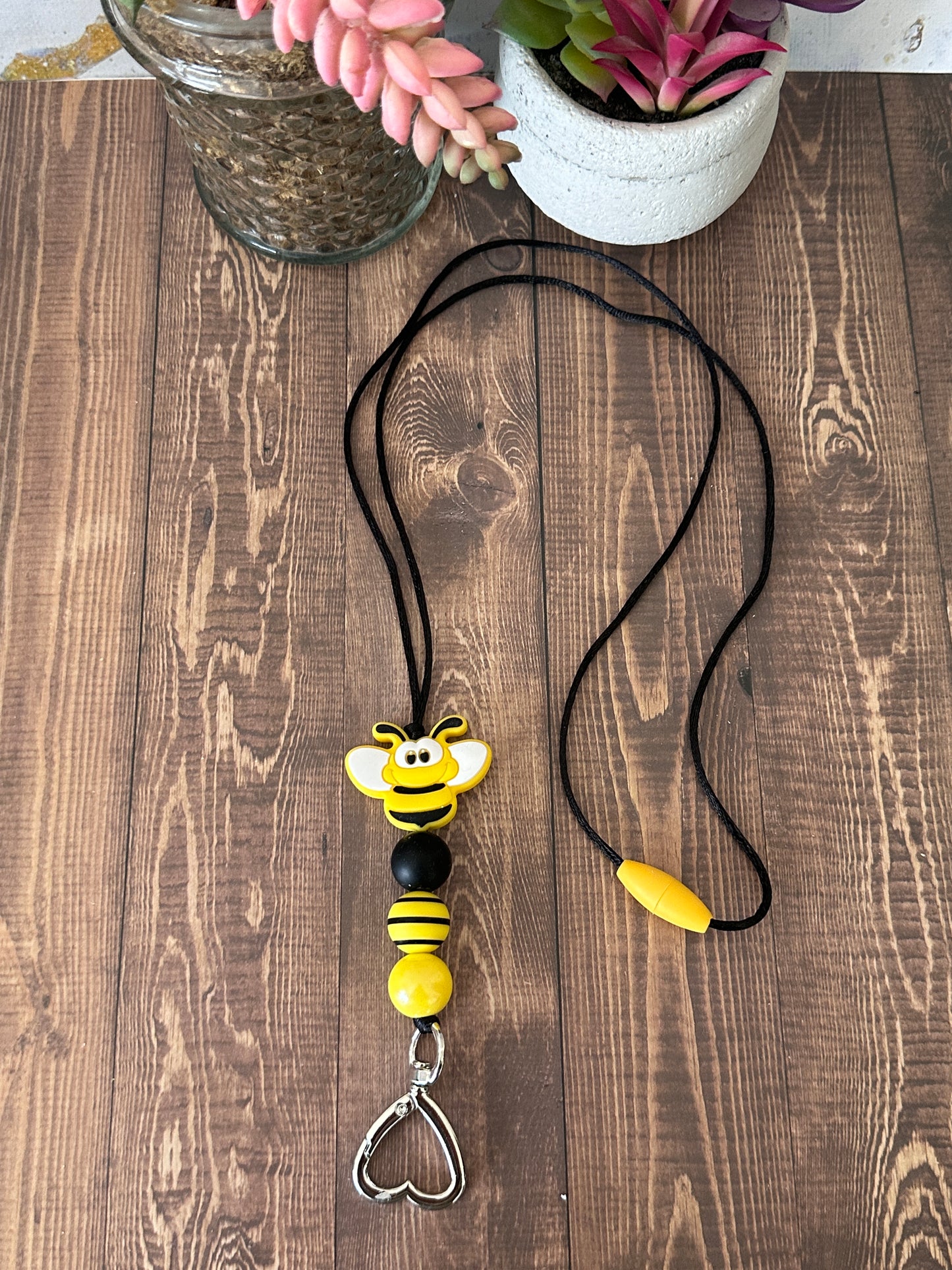 Handcrafted bumble bee teacher lanyard laying flat showing full beaded design, safety clasp, and heart key holder.