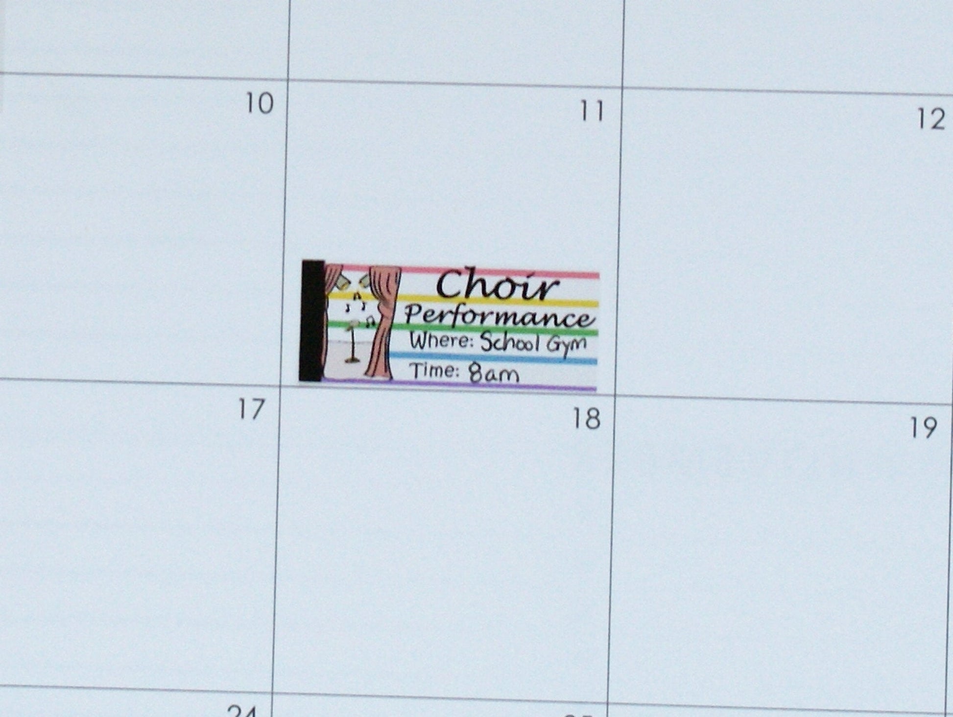 Close up of choir performance reminder sticker placed in music teacher planner for concert date and location tracking.