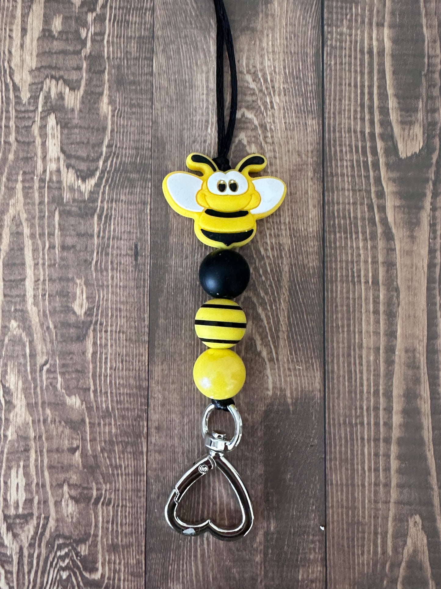 Close-up of bumble bee charm and metal clasp on handmade teacher lanyard, premium beaded construction detail.