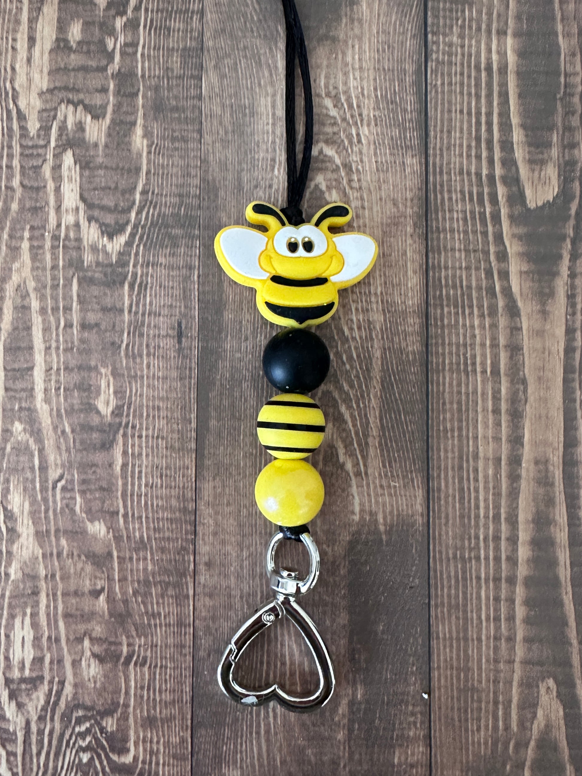 Close-up of bumble bee charm and metal clasp on handmade teacher lanyard, premium beaded construction detail.