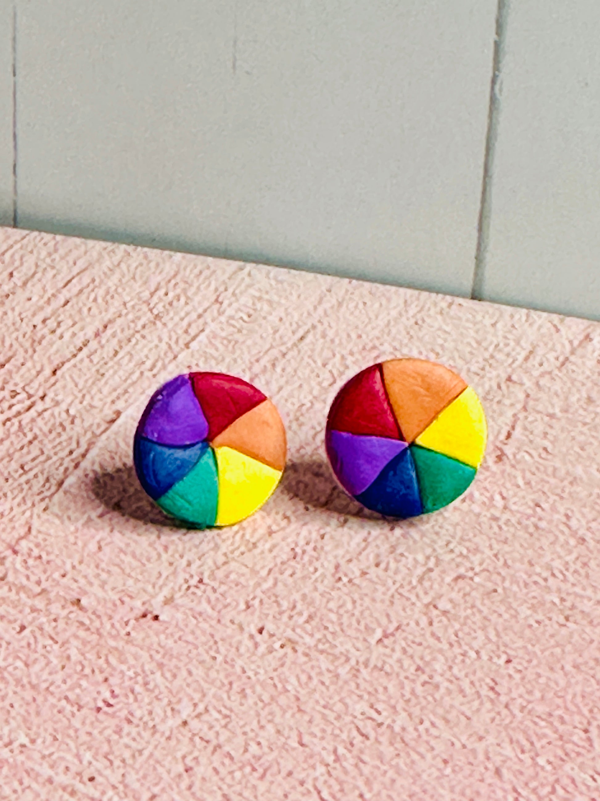 Zoomed-out view of Color Wheel Stud Earrings displayed on pink table surface showing full earring size and proportions.