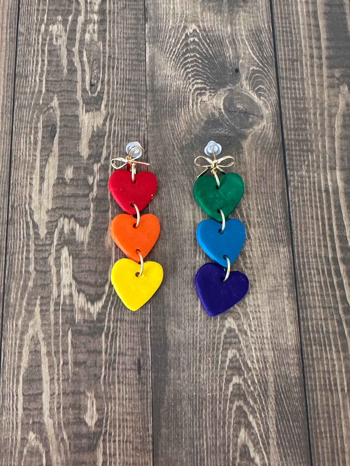 Colorful heart-shaped earrings on a wooden surface