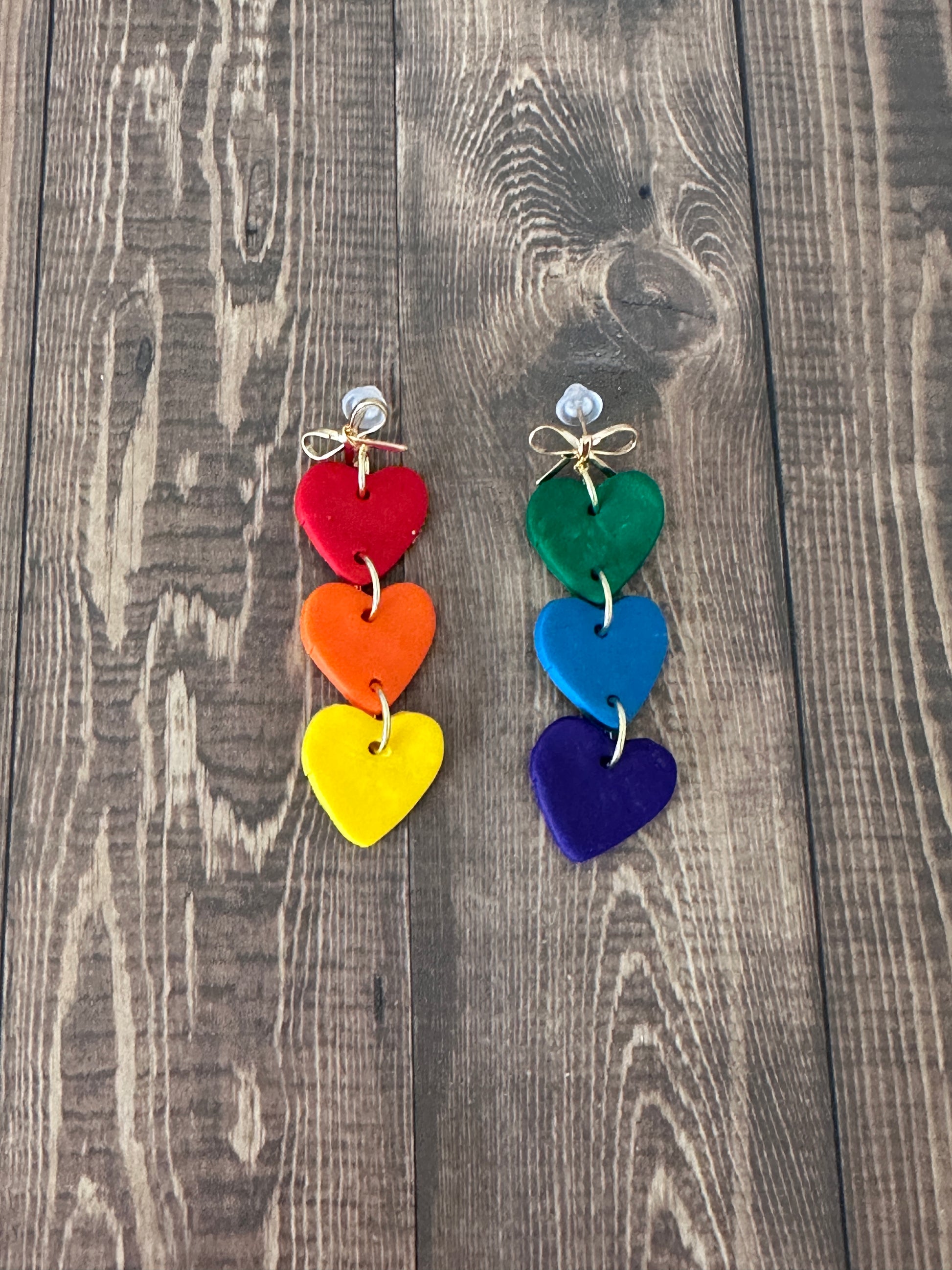 Colorful heart-shaped earrings on a wooden surface