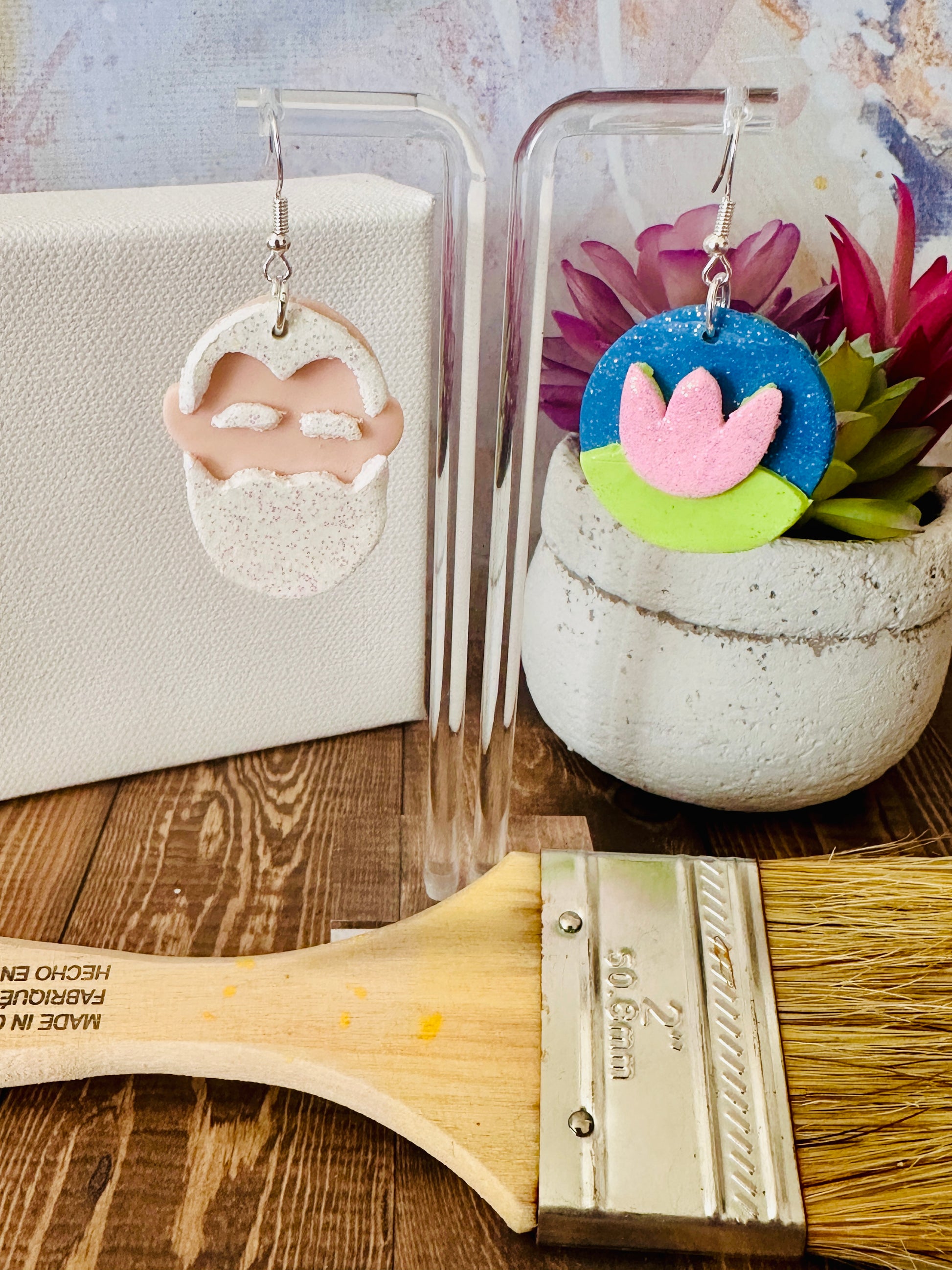 Detailed close up of handmade Claude Monet portrait and water lily art teacher earrings with paintbrush and plants.