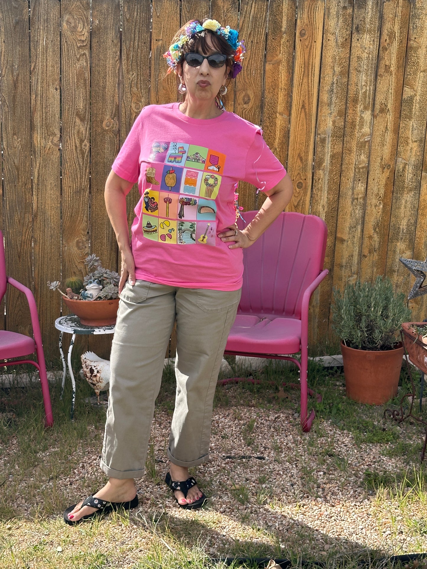 Woman wearing the pink Fiesta San Antonio Lotería shirt with khaki pants and a Fiesta halo. 