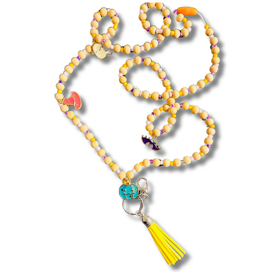 A Halloween-themed lanyard featuring wooden beads, a colorful tassel, and charms including a pumpkin, bat, witch hat, and ghost.