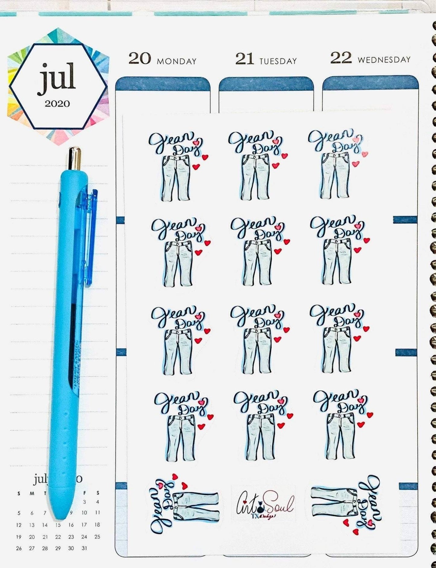 Close Up Detail
Alt Text: Jean Day reminder sticker sheet next to blue pen inside open teacher planner close-up view.