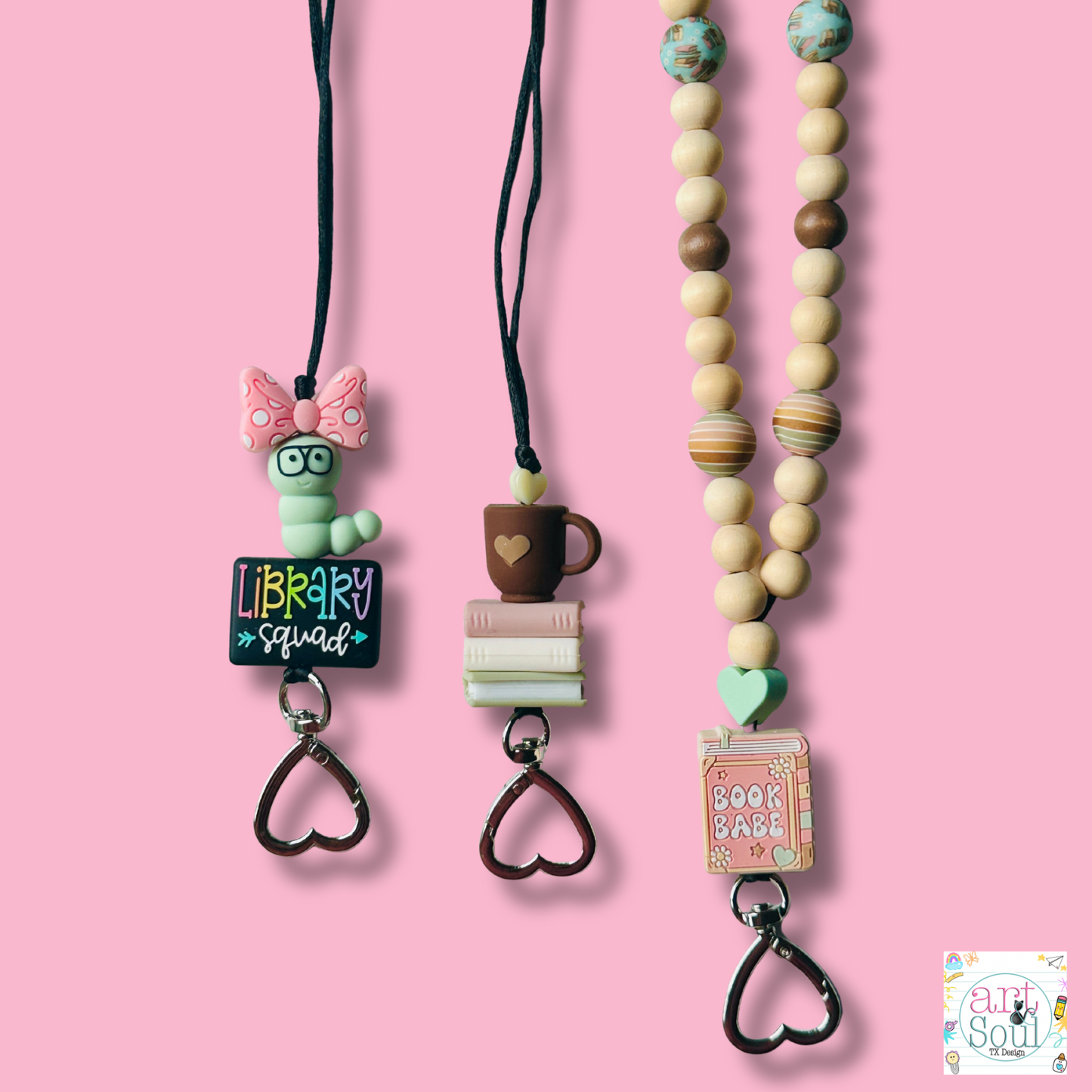 Three colorful book lanyards with cute book related shapes like bookworm, books, and coffee cup on a pink background.