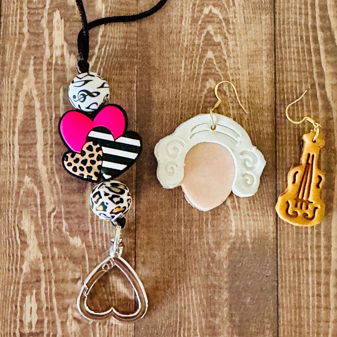Decorative music lanyard on the left and a pair of Mozart earrings on the right resting  on a wooden surface.
