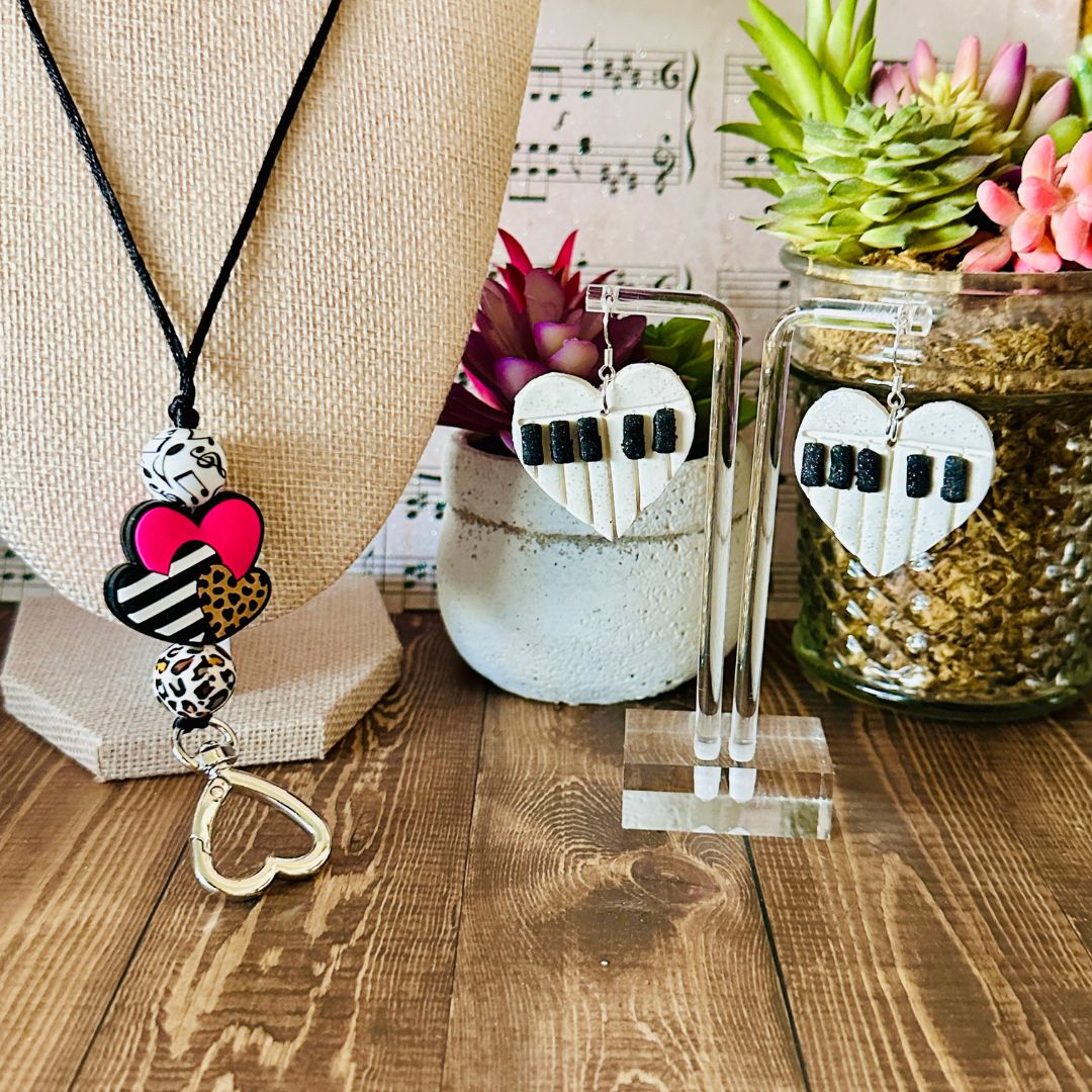 Necklace with heart-shaped beads and earrings on a wooden surface with plants in the background