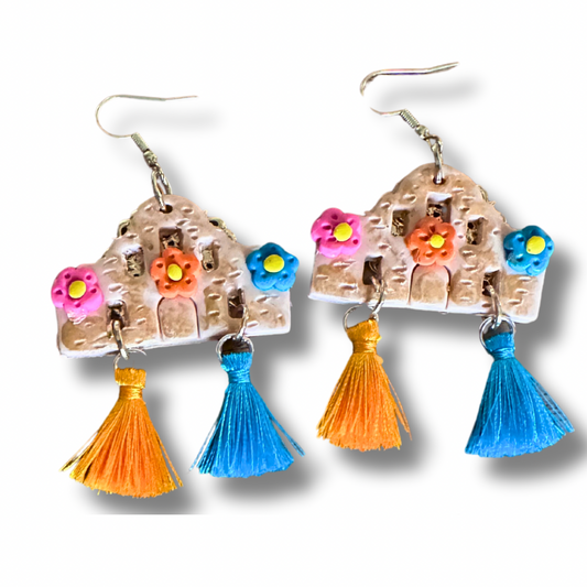 Handmade Alamo-shaped earrings in with decorative clay flowers, filigree backing, and orange and blue decorative tassels.