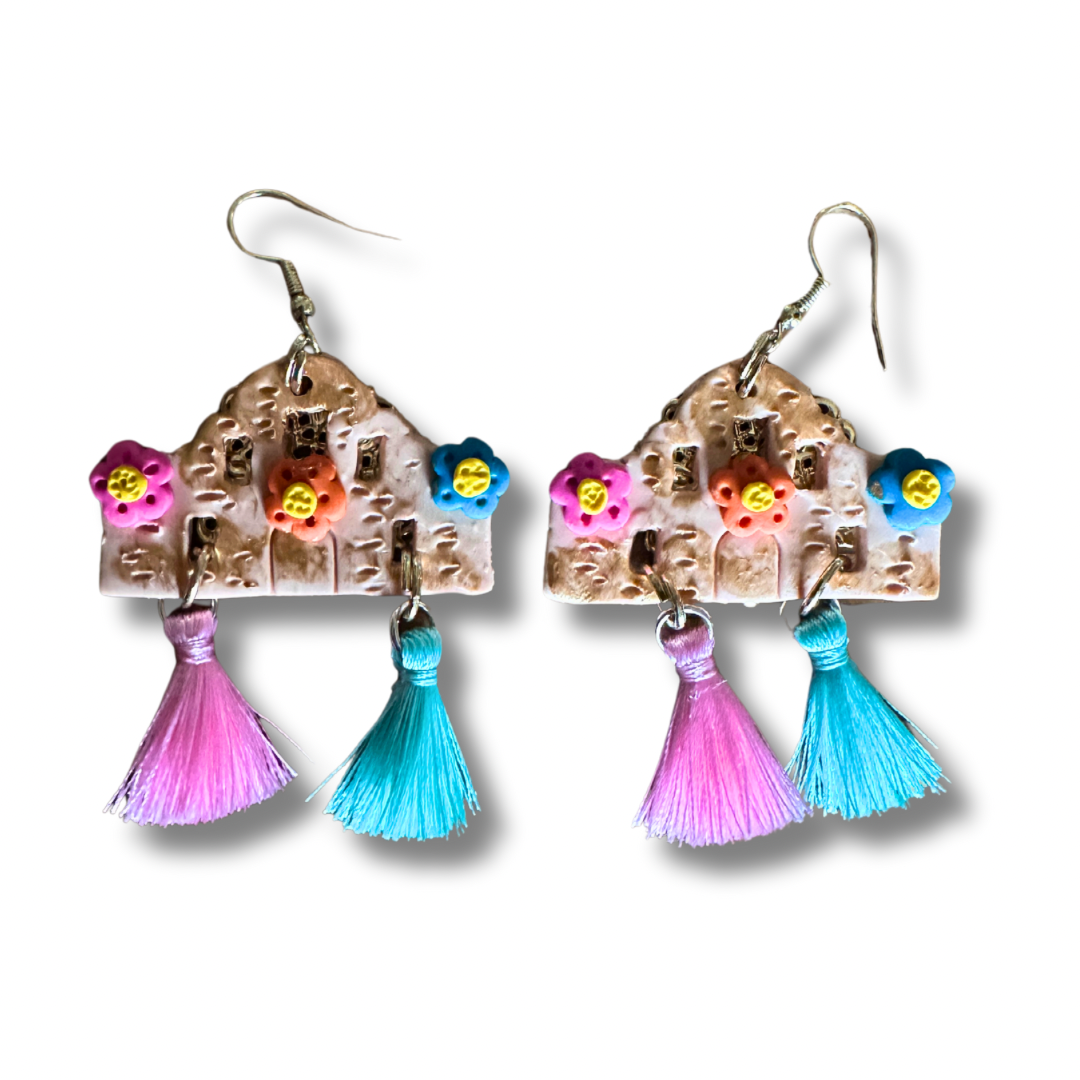 Handmade Alamo-shaped earrings in with decorative clay flowers, filigree backing, and pink and teal decorative tassels.