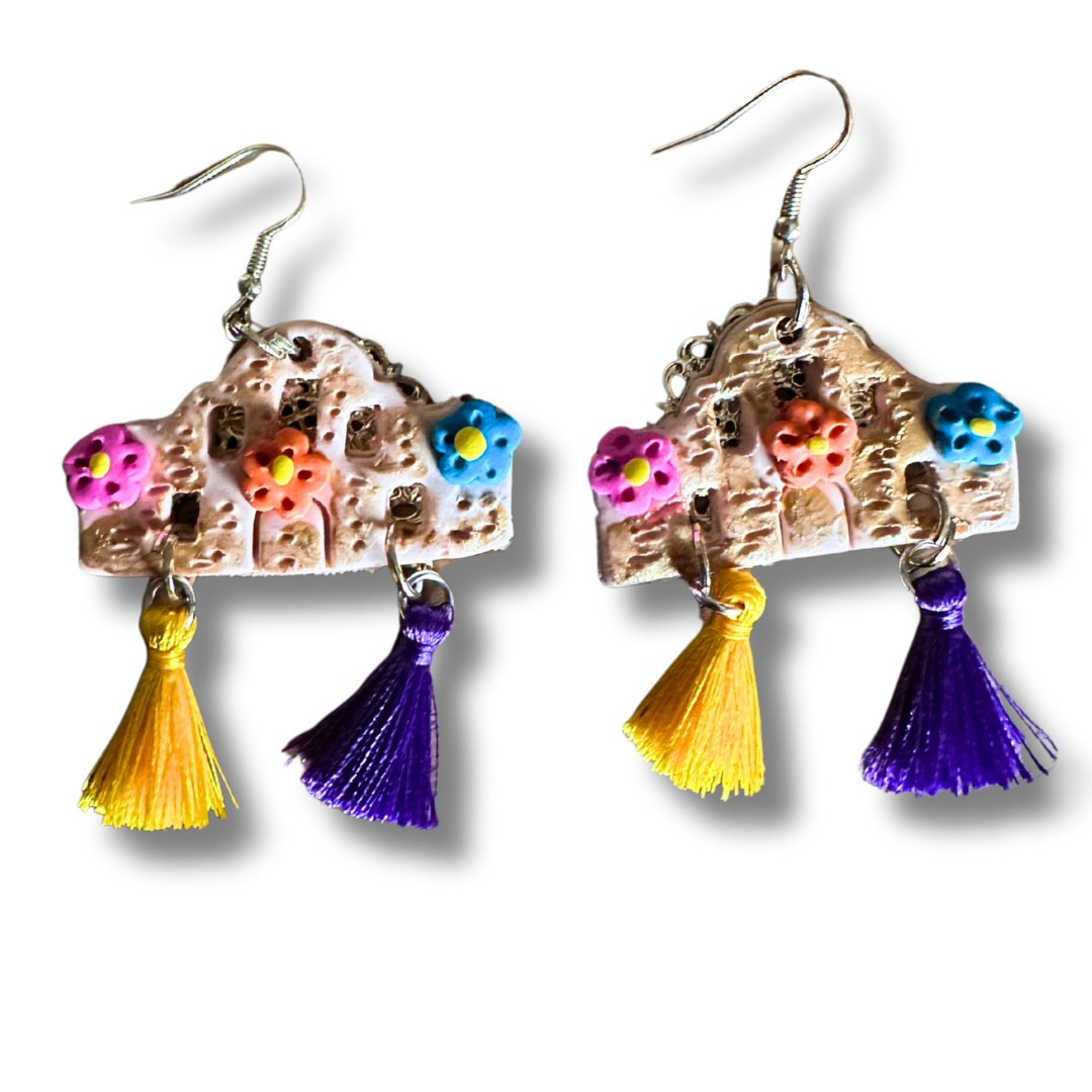 Handmade Alamo-shaped earrings in with decorative clay flowers, filigree backing, and yellow and purple decorative tassels.