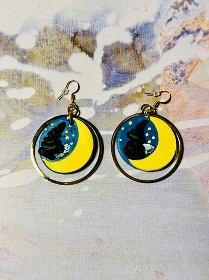 A pair of Van Gogh Starry Night earrings on an abstract colored background.