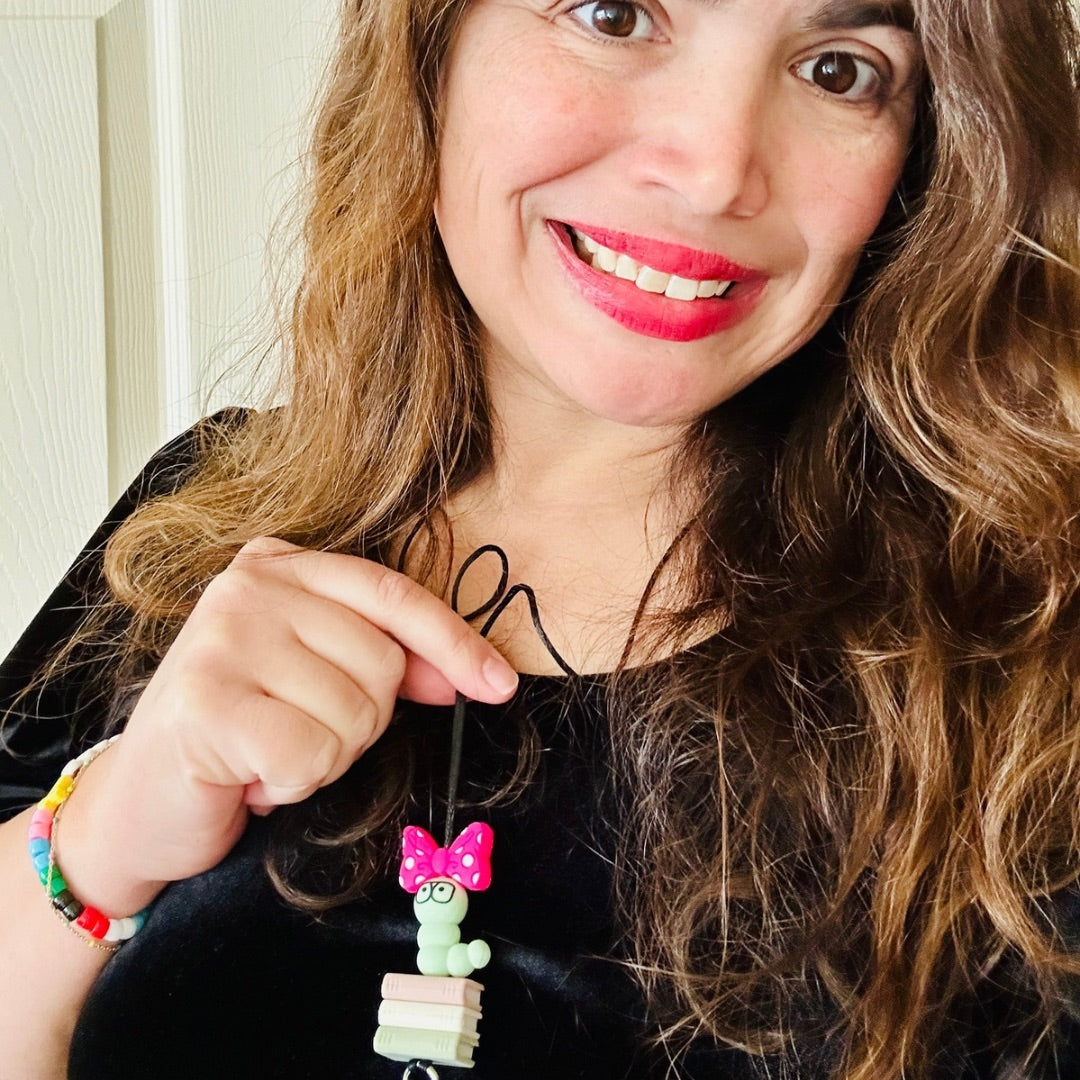 Woman holding a colorful silicone beaded book worm lanyard with a pink bow.