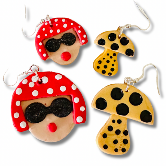 Size comparison of Yayoi Kusama polymer clay earrings showing large and small variants with portrait, red polka dot hair, and yellow mushroom on white background.