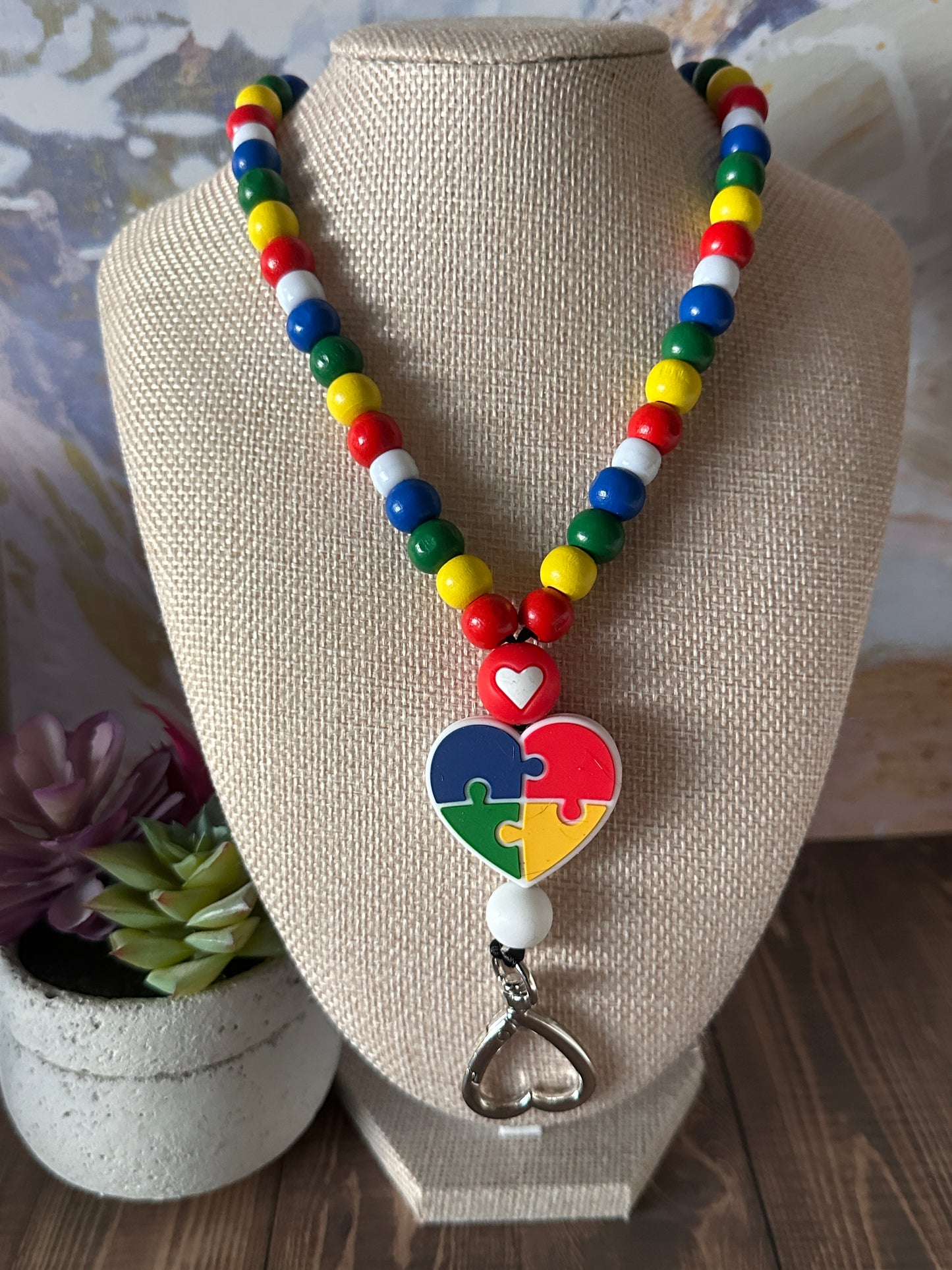 Rainbow beaded autism awareness lanyard worn on mannequin highlighting colorful puzzle piece heart silicone bead.