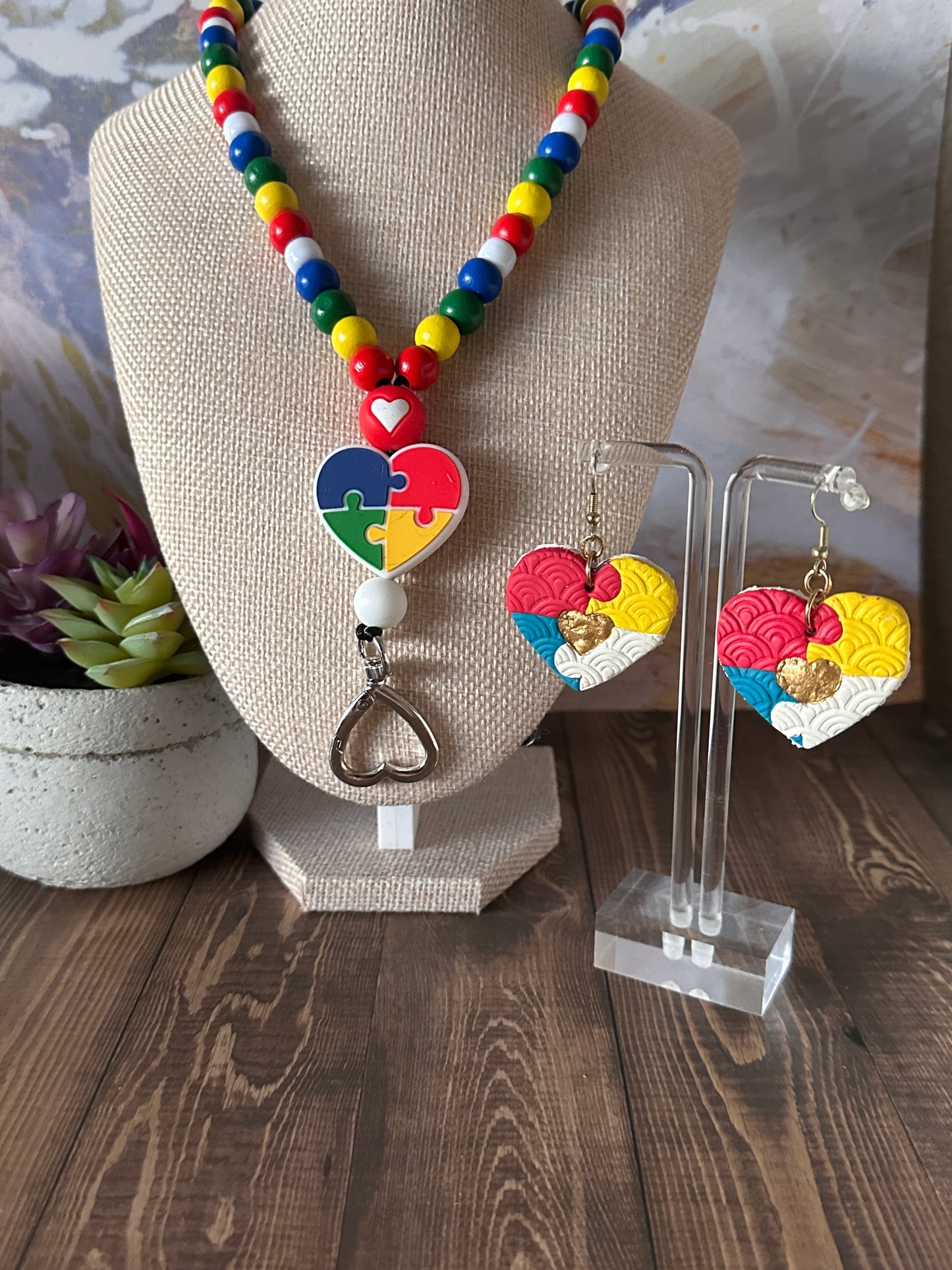 Rainbow beaded autism awareness lanyard styled on mannequin with matching puzzle piece autism awareness earrings.