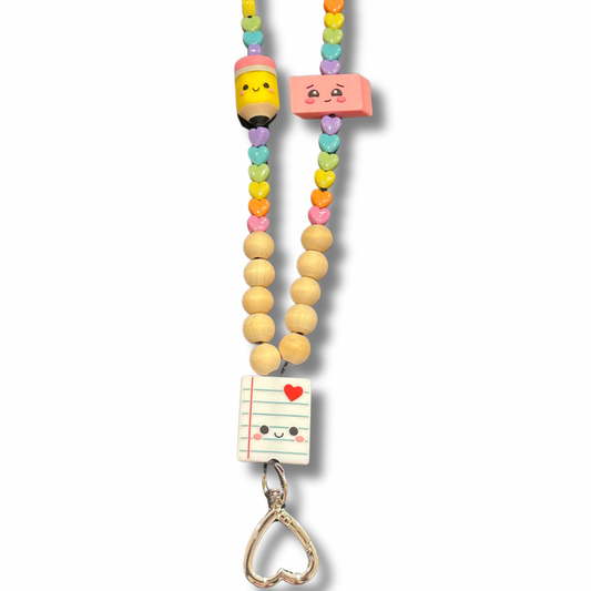 Close-up of cute teacher lanyard with light wooden beads, pastel rainbow heart beads, silicone pencil eraser and notebook beads, and heart-shaped breakaway clasp.