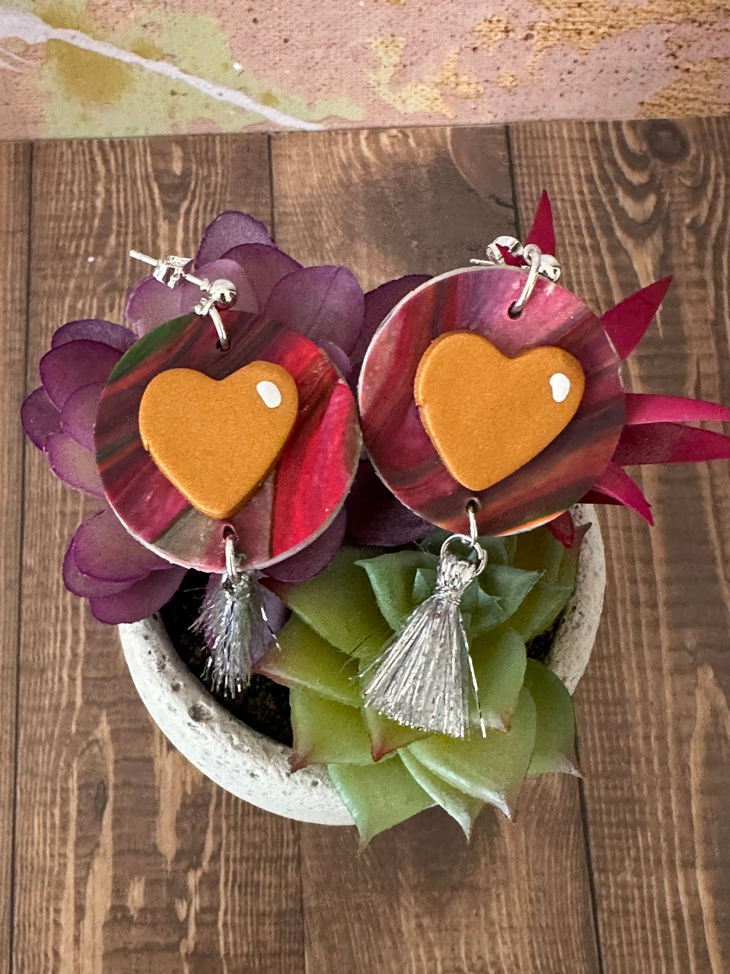 Jim Dine-inspired polymer clay heart earrings displayed on a potted succulent on a wooden table