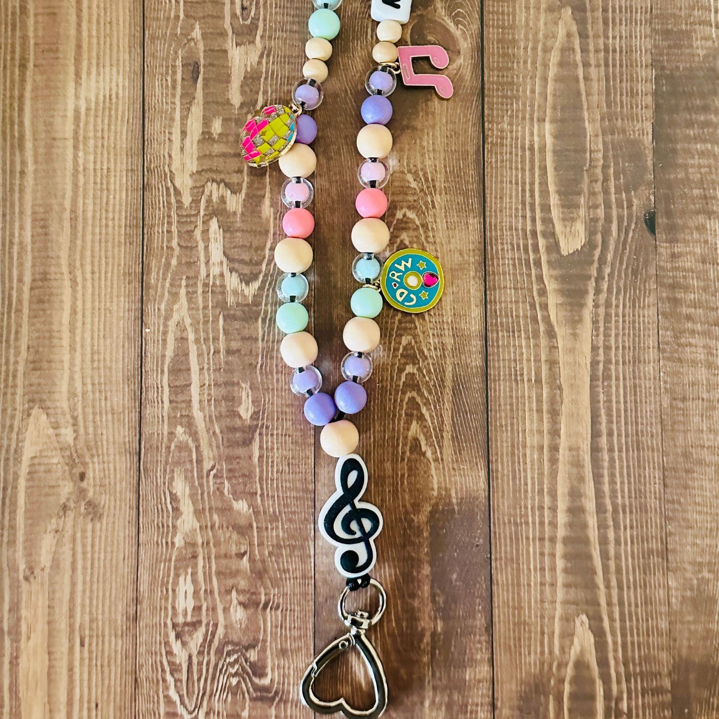 Close Up of a colorful beaded lanyard with various charms on a wooden surface