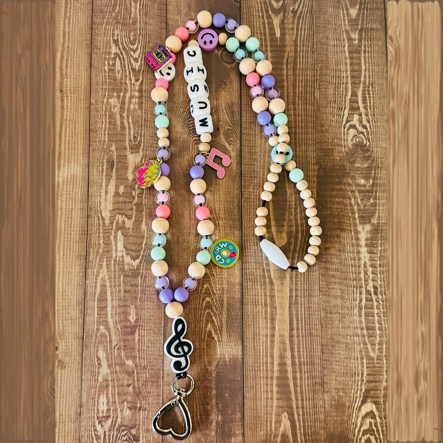 Colorful beaded necklace with music-themed charms on a wooden surface