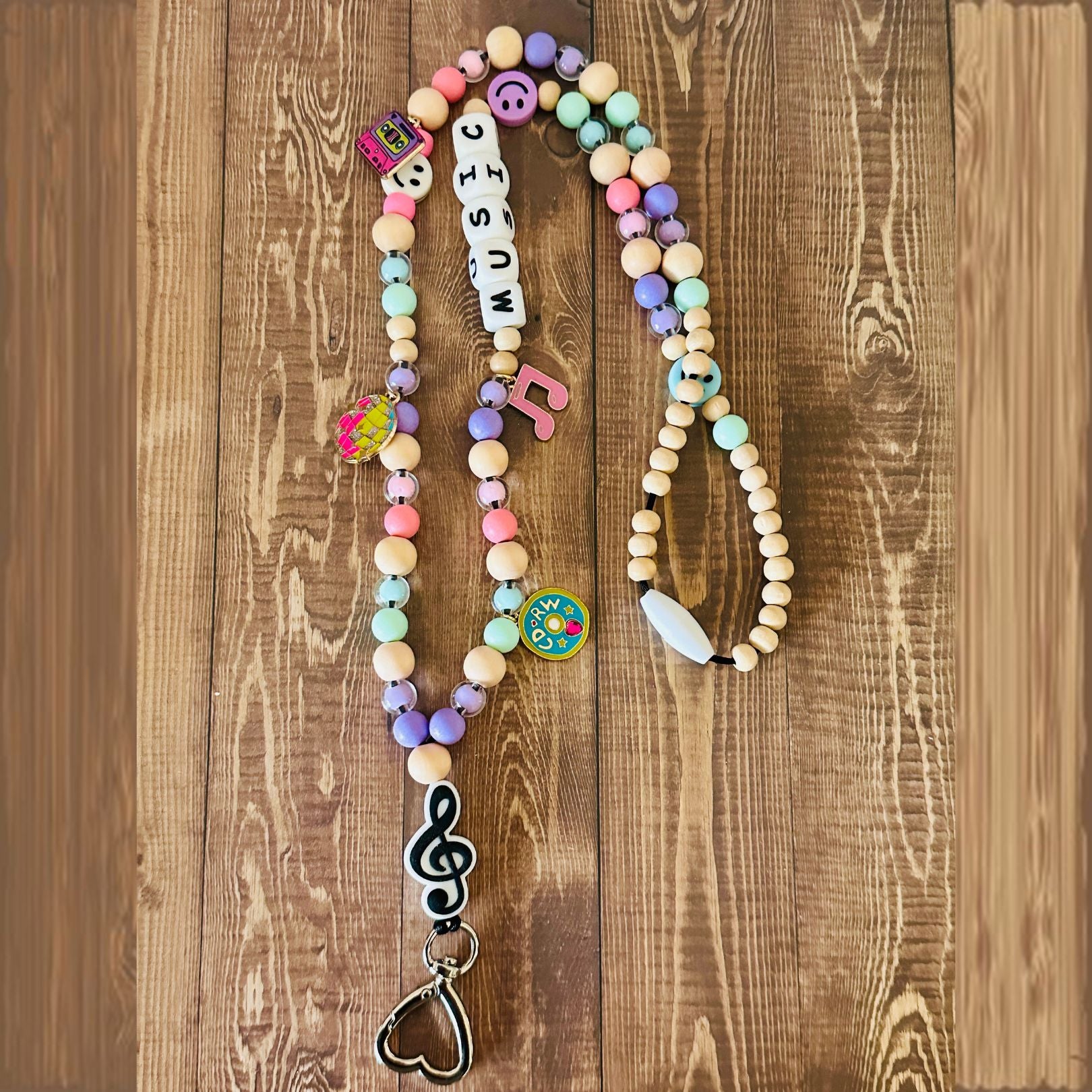 Colorful beaded necklace with music-themed charms on a wooden surface
