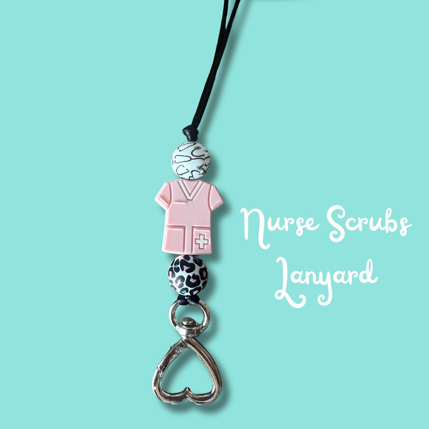 Close-up of nurse scrubs silicone beads and heart clasp on handmade beaded ID badge lanyard, light blue background.
