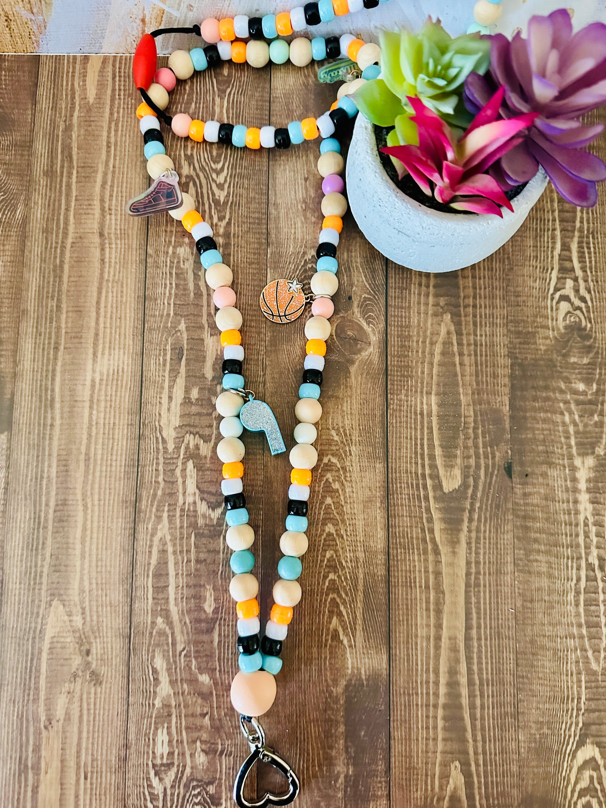 P.E. teacher beaded lanyard all star sports charms flat on wooden teacher desk with succulent
