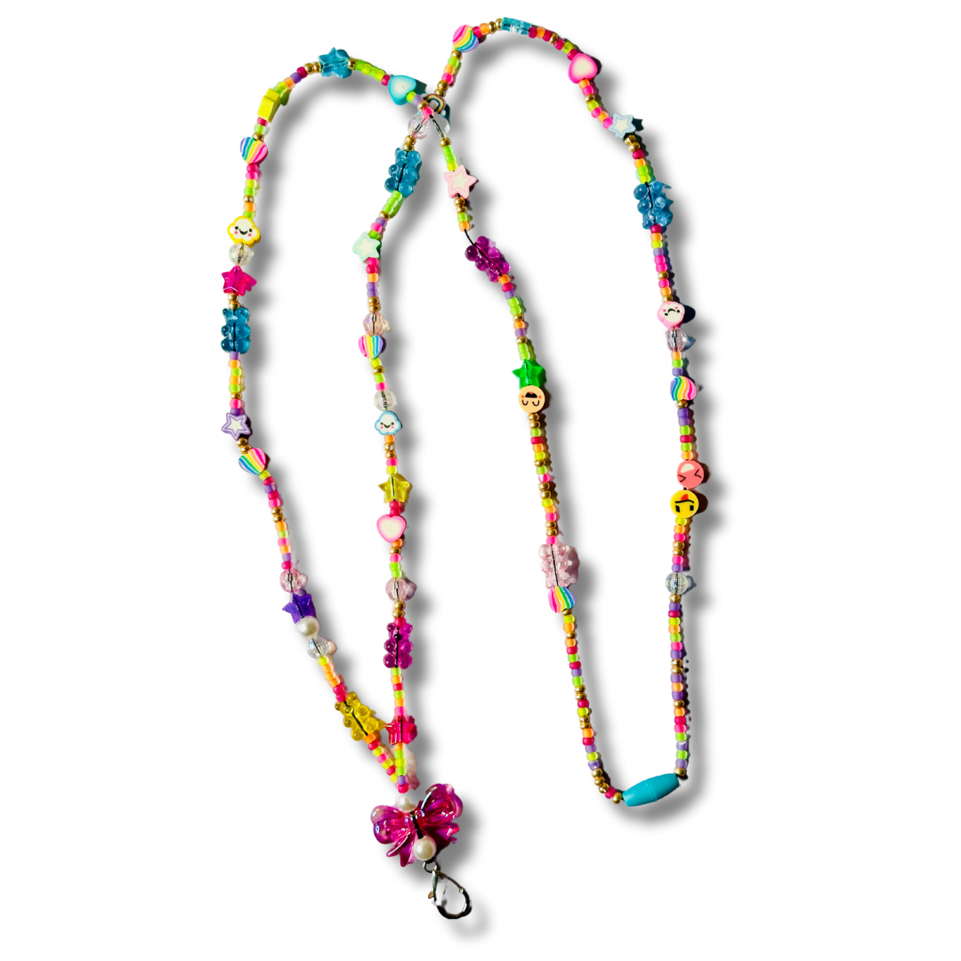 Handmade pink bow beaded lanyard with rainbow silicone bear, heart, cloud, and smiley face beads, metal keychain, and breakaway clasp on a white background.