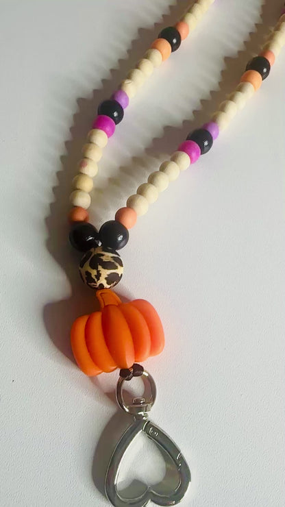 Video demonstration showcasing three different Halloween themed beaded lanyards with various color schemes and charm combinations, featuring the trick or treat lanyard as the second item displayed, showing movement and bead details.