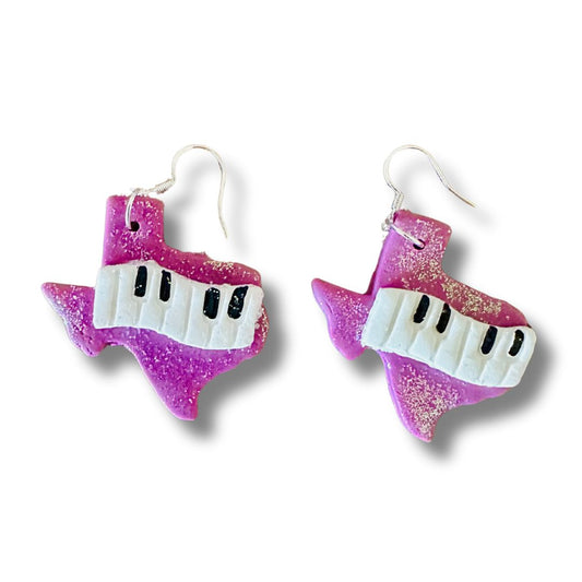 Purple glittery Texas piano key earrings on a white background