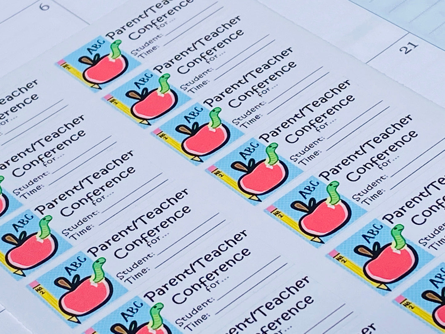 Zoomed angled view of parent-teacher conference stickers laying in a teacher planner, showing apple design and writable lines for meeting details.